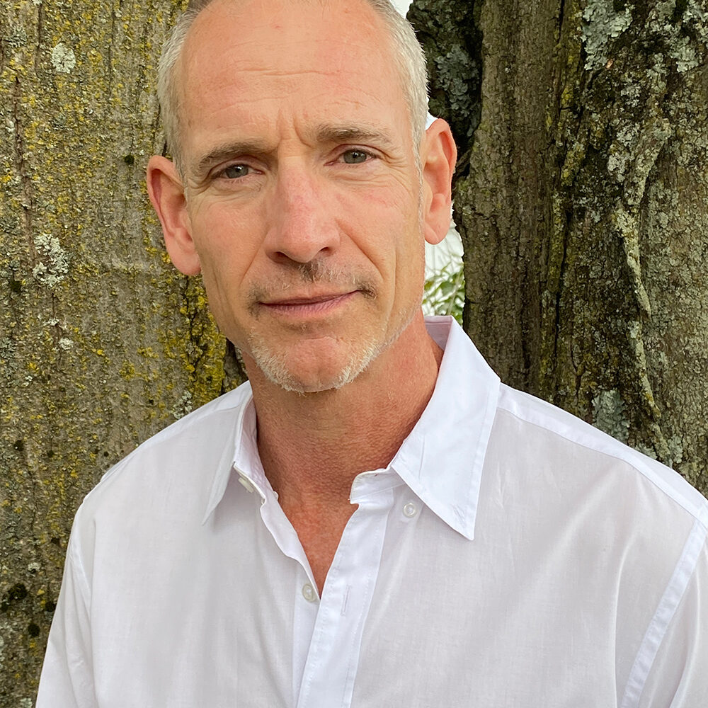 portrait photo of John sitting in front of a tree